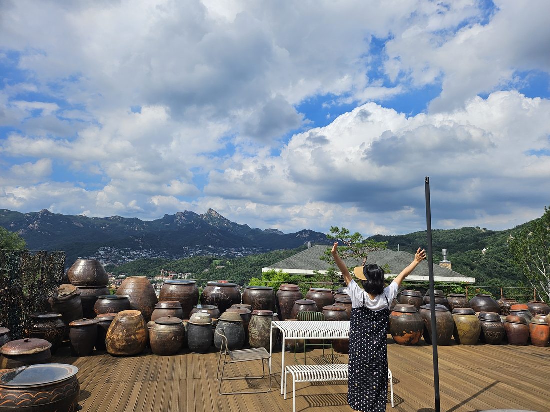 Rows of onggi jars on a Seoul rooftop jangdokdae, Bukak mountain rising behind.